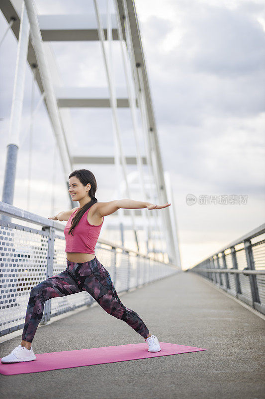 年轻有魅力的女人练习瑜伽，站在勇士两个运动，Virabhadrasana II姿势，锻炼和穿着运动服